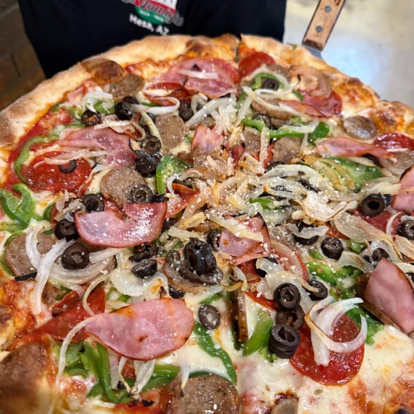 Close-up of a La Famiglia pizza with pepperoni, ham, sausage, green peppers, onions, and olives.
