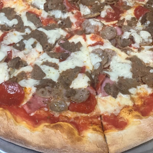 A close-up of a La Famiglia Pizza & Pasta pizza, topped with pepperoni, sausage, and ham.