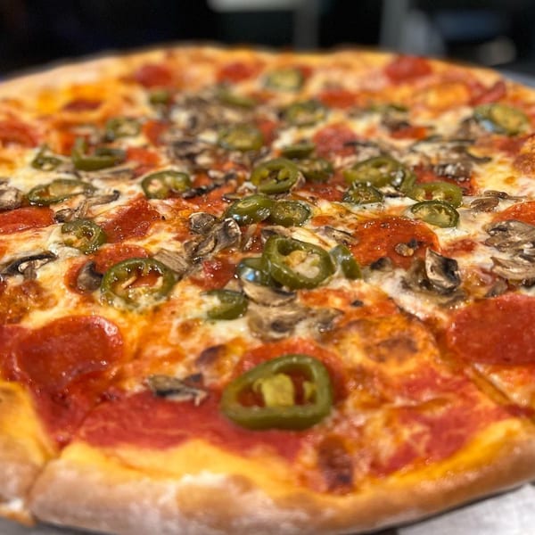 A close-up of a La Famiglia pizza with pepperoni, mushrooms, and jalapeños.