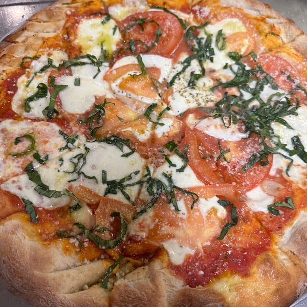 La Famiglia's Margherita pizza, topped with fresh mozzarella, sliced tomatoes, and basil.