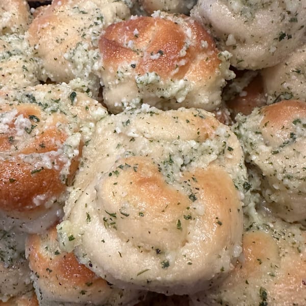 Close-up of La Famiglia's garlic knots, golden-brown and glistening with garlic butter and herbs.