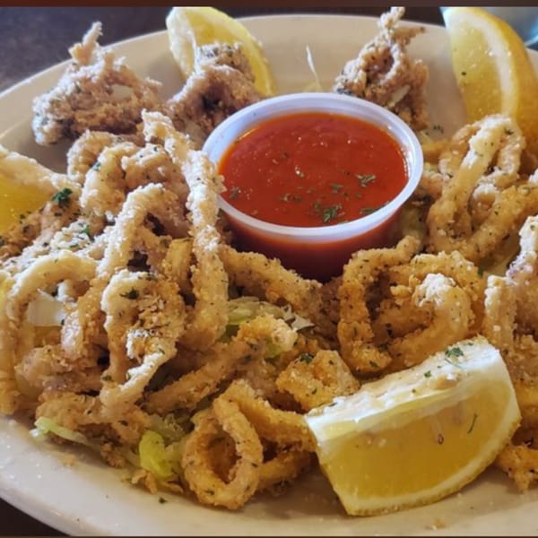Crispy fried calamari rings and tentacles with lemon wedges and a side of marinara sauce.