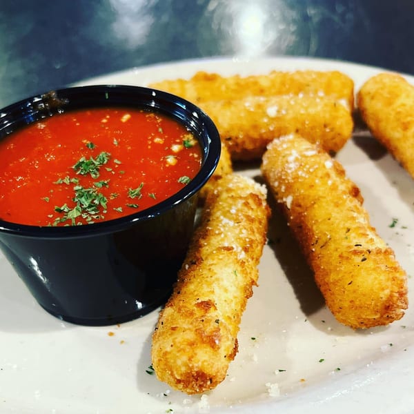 Golden-brown mozzarella sticks, sprinkled with herbs and cheese, served with a side of marinara sauce.